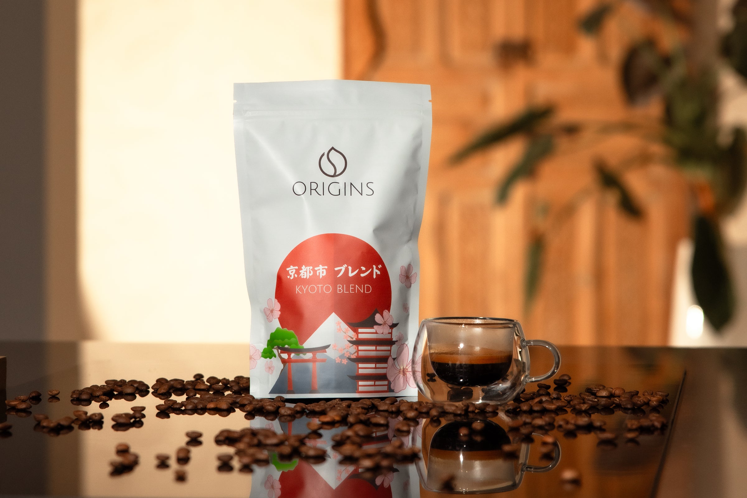 Coffee bag labeled 'Origins' with a cup of coffee and scattered coffee beans on a reflective surface.