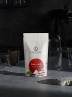 Origins coffee package on a dark background with glassware